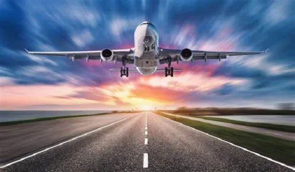 Passenger aircraft coming in to land over an open road at sunset