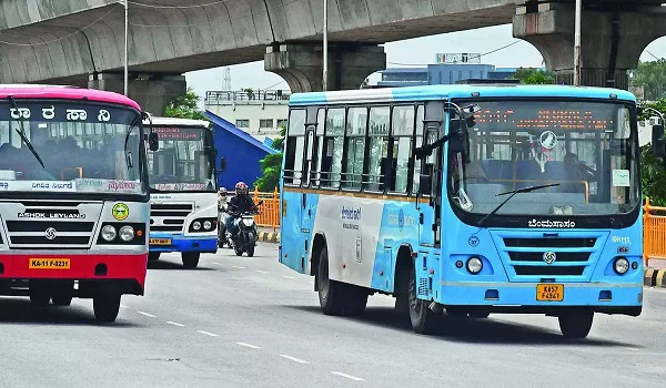BMTC city buses on a wide Bangalore arterial road beneath an elevated corridor