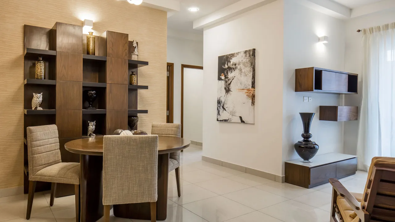 Furnished apartment interior with a dining table, display shelving and a naturally lit living area &mdash; representative image of the apartment format planned at Prestige Bangalore