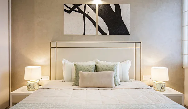 Bedroom with an upholstered headboard, matching bedside lamps and framed artwork above the bed
