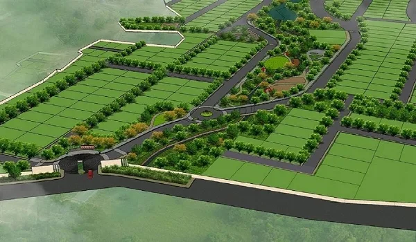 Aerial view of a plotted residential development with marked plots, tree-lined internal roads and a gated entrance beside a waterway