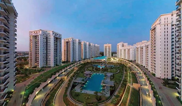 High-rise residential towers around a landscaped central garden and swimming pool at dusk, in a completed Prestige Group development